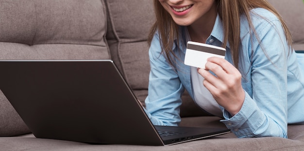 Foto mulher segurando laptop e cartão de crédito vista frontal