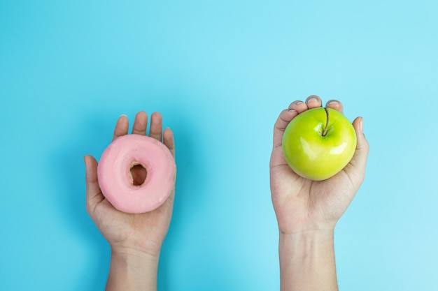 Mulher segurando maçã verde e rosquinha rosa