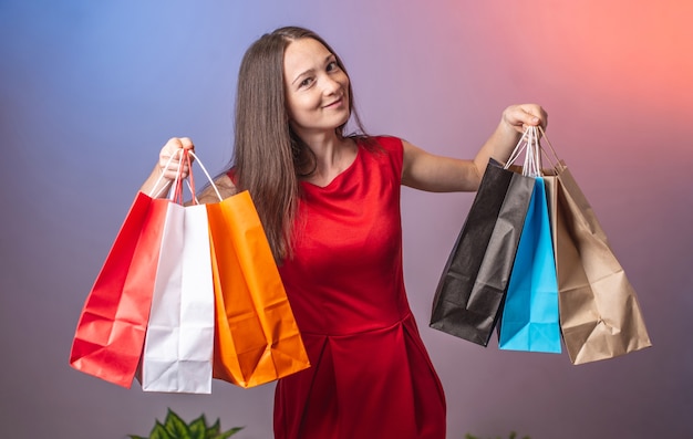 Mulher segurando muitos sacos de papel multicoloridos com compras