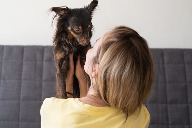 Mulher segurando o abraço engraçado brown toy terrier. conceito de cuidados de animais de estimação. amor e amizade