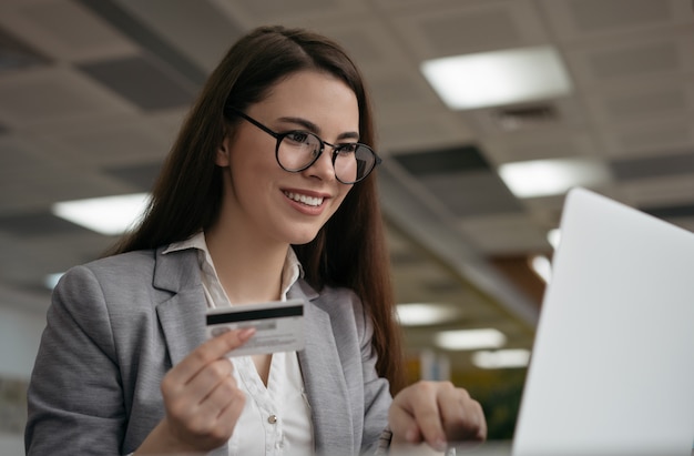 Mulher segurando o cartão de crédito, compras on-line, reserva de bilhetes no site