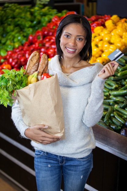 Foto mulher segurando o cartão de crédito e sacola de compras