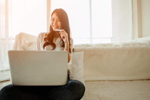 Mulher segurando o cartão de crédito e usando o laptop para fazer compras online.