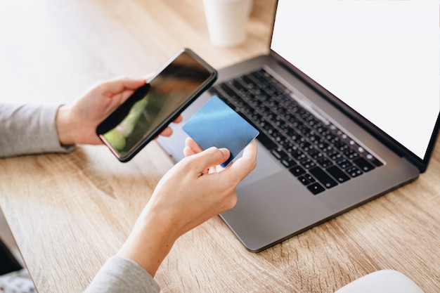 Mulher segurando o cartão de crédito enquanto paga para fazer compras no smartphone