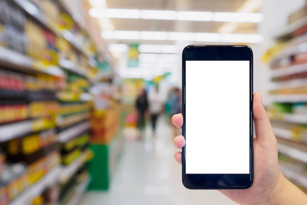 Mulher segurando o celular enquanto faz compras no supermercado