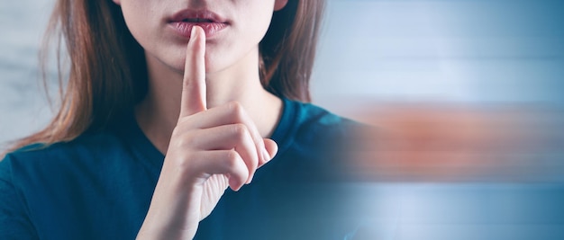 Mulher segurando o dedo nos lábios mostrando o gesto de silêncio