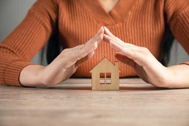 Mulher segurando o modelo de casa Conceito de seguro imobiliário e residencial