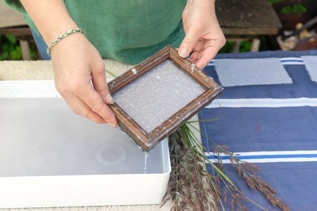 Mulher segurando o quadro para fazer folhas de papel de polpa de papel residual. foco seletivo. arte decorativa e aplicada. conceito de reciclagem, ecologia.