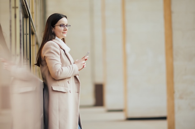 Mulher segurando o telefone contra uma janela panorâmica