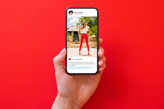 Foto mulher segurando o telefone na mão com foto de modelo de moda em calças vermelhas sobre fundo vermelho