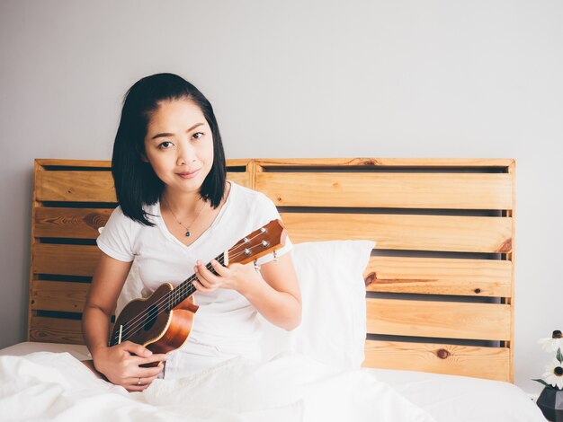 Mulher segurando o ukulele em seu quarto aconchegante.