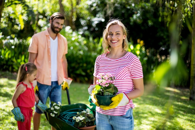 Mulher segurando o vaso de flores com a família no quintal