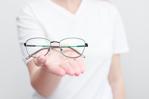 Mulher segurando óculos de close-up na mão em um fundo branco