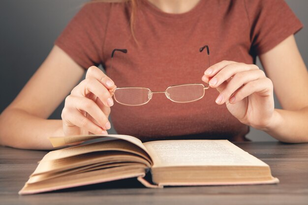 Mulher segurando óculos na frente de um livro