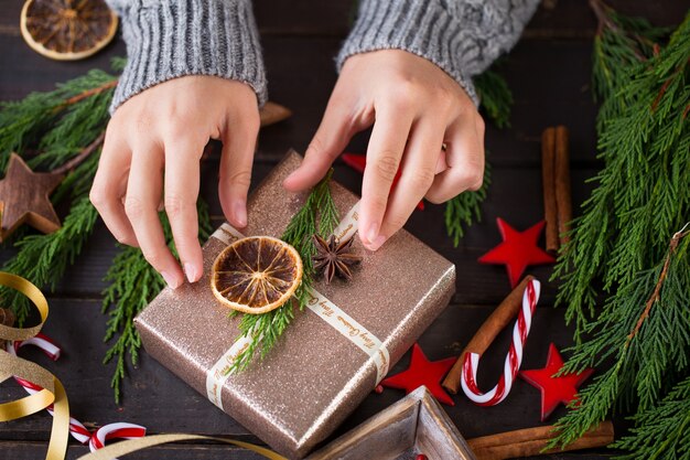 Mulher segurando os presentes de Natal colocados sobre um fundo de mesa de madeira.