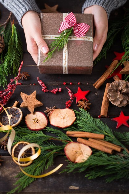 Mulher segurando os presentes de Natal colocados sobre uma mesa de madeira.