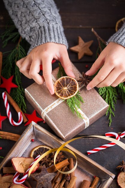 Mulher segurando os presentes de Natal colocados sobre uma mesa de madeira.