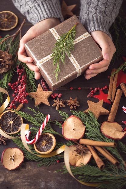 Mulher segurando os presentes de Natal colocados sobre uma mesa de madeira.