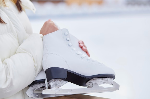 Mulher segurando patins de gelo lá fora no inverno perto da pista de patinação Conceito de sonho de estilo de vida ativo