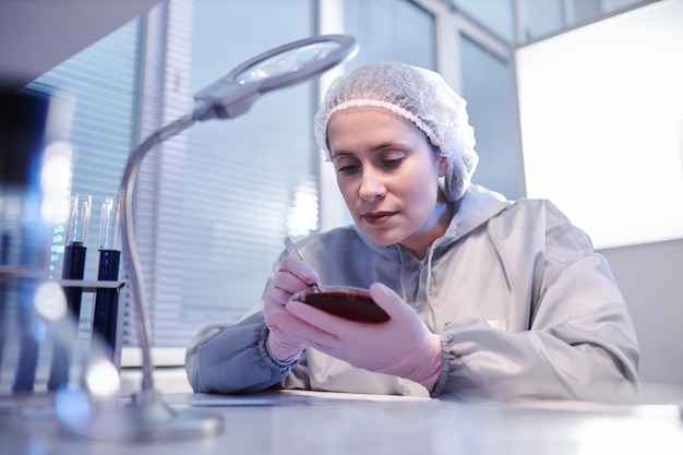 Mulher segurando placa de petri fazendo pesquisa biológica em laboratório