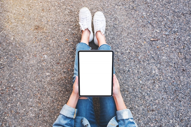 Mulher segurando preto tablet pc com branco em branco enquanto está sentado na rua ao ar livre