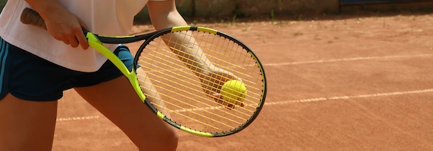 Mulher segurando raquete e bola de tênis na quadra de saibro