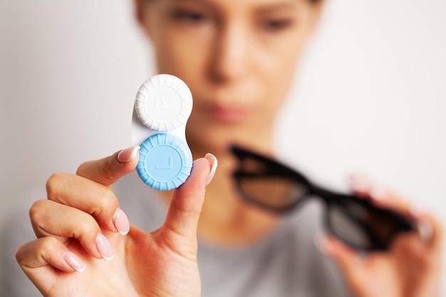 Mulher segurando recipiente de plástico com lentes de contato