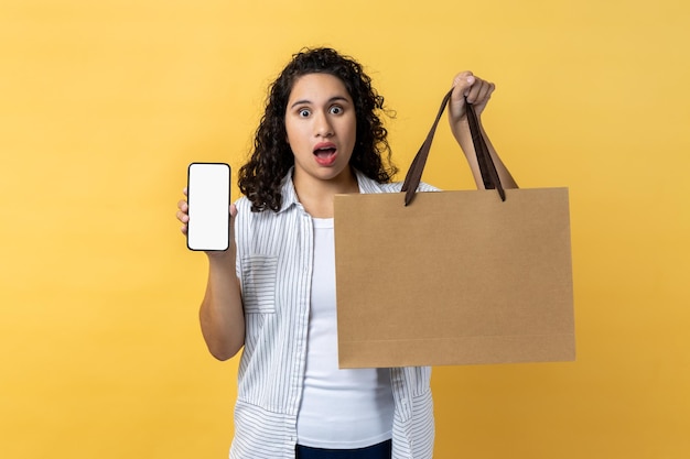 Mulher segurando sacola de papel e celular com espaço de cópia de tela vazio para promoção