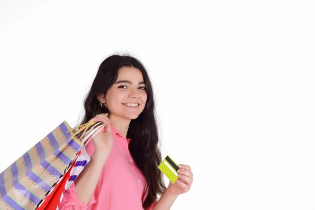 Mulher segurando sacolas de compras e cartão de crédito.