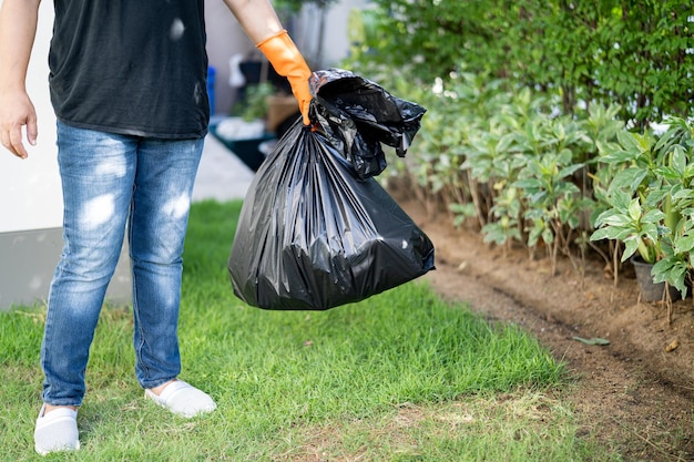 Mulher segurando sacos de lixo plástico preto de lixo no conceito de ambiente limpo de pavimento