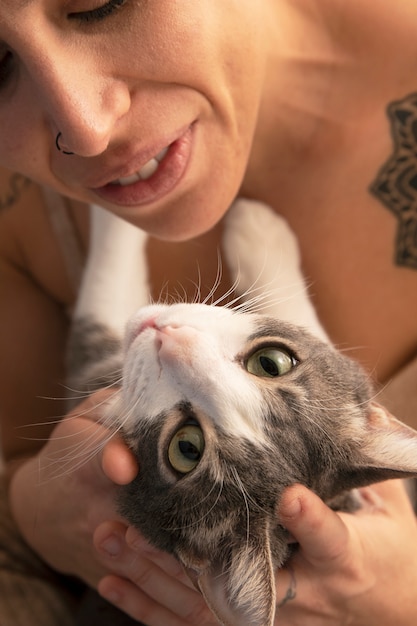 Foto mulher segurando seu adorável gatinho dentro de casa