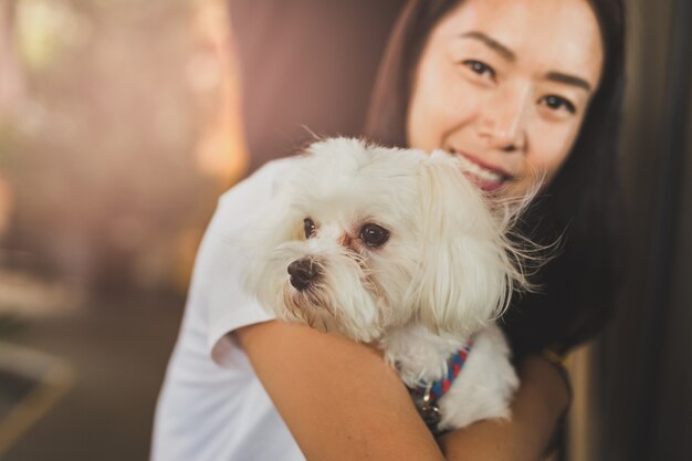 Mulher segurando seu cachorro branco shih tzu