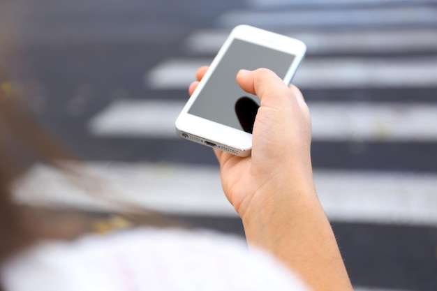 Mulher segurando smartphone do lado de fora