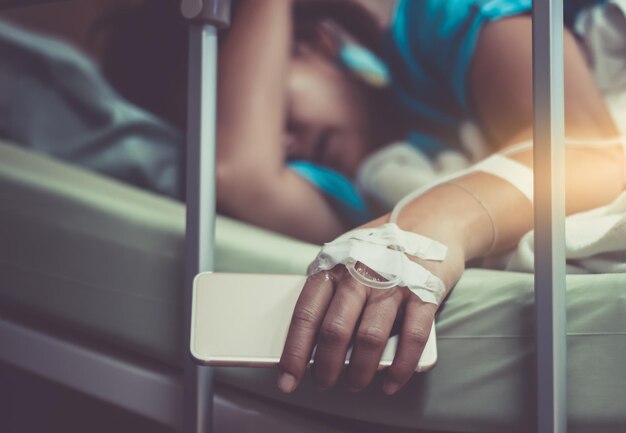 Foto mulher segurando smartphone enquanto deitada na cama no hospital