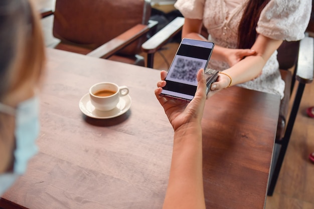 Mulher segurando smartphone perto de máquina de pagamento eletrônico