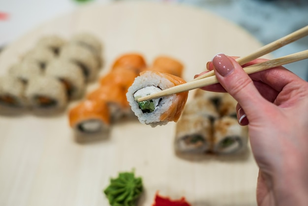 Mulher segurando sushi na mão com pauzinhos