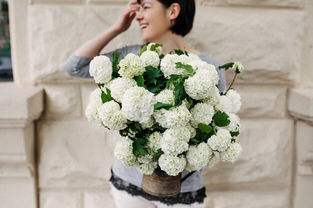 Mulher segurando um balde com flores de hortênsia