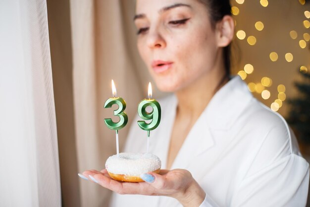 Mulher segurando um bolo com o número 39 velas no fundo festivo bokeh turva