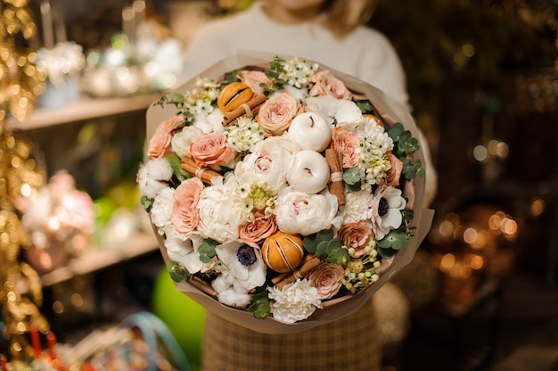 Mulher segurando um buquê de rosas brancas e cor de pêssego decorado com maçãs