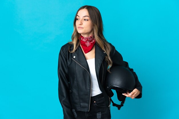 Mulher segurando um capacete de motociclista isolada olhando para o lado