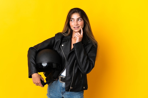 Mulher segurando um capacete de motociclista isolado em fundo amarelo