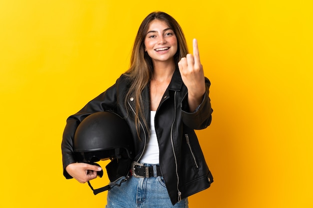 Foto mulher segurando um capacete de motociclista isolado na parede amarela fazendo gesto de aproximação