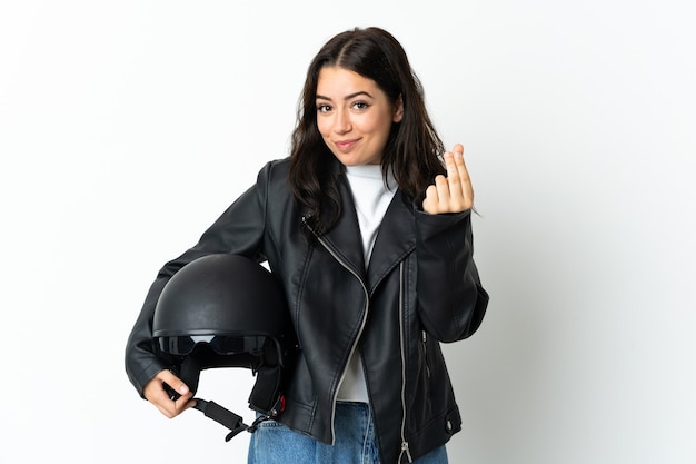 Mulher segurando um capacete de motociclista isolado na parede branca fazendo gesto de dinheiro