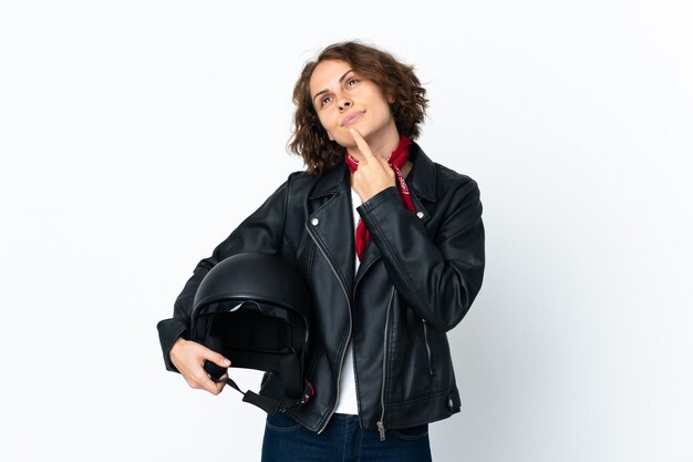 Mulher segurando um capacete de motociclista posando isolado contra a parede em branco