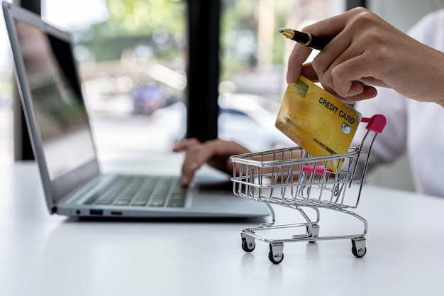 Mulher segurando um cartão de crédito e digitando em um teclado de laptop, ela está preenchendo as informações do cartão de crédito para pagar um pedido em um site de compras na Internet. Conceito de compras online e pagamento com cartão de crédito