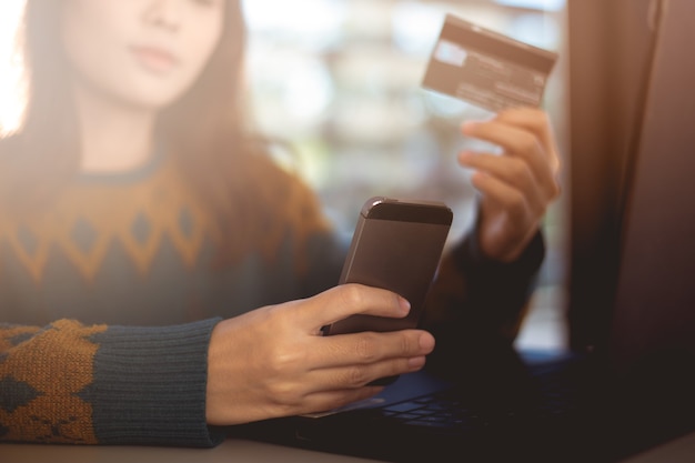 Foto mulher segurando um cartão de crédito e usando o smartphone para fazer compras online