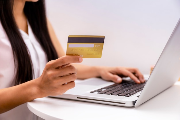 Mulher segurando um cartão de crédito e usando um laptop