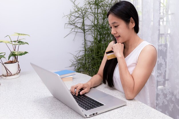 Mulher segurando um cartão de crédito e usando um laptop