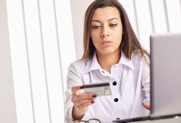 Mulher segurando um cartão de crédito no laptop para o conceito de compras online