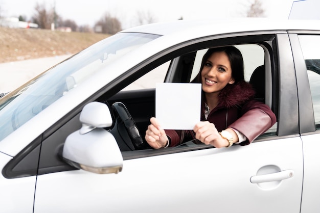 Mulher segurando um cartaz branco em branco no carro